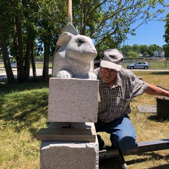 Thomas Berger, sculptor, lowers his sculpture onto a pedestal